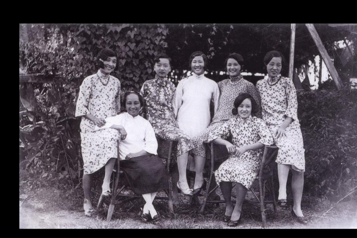 Black and white photo. Seven women standing together and smiling. 