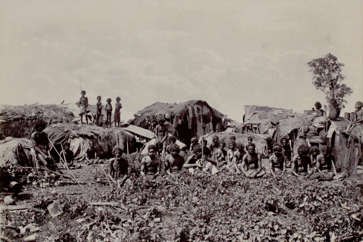 Depicts a group of Aboriginal men, women and children within a camp.