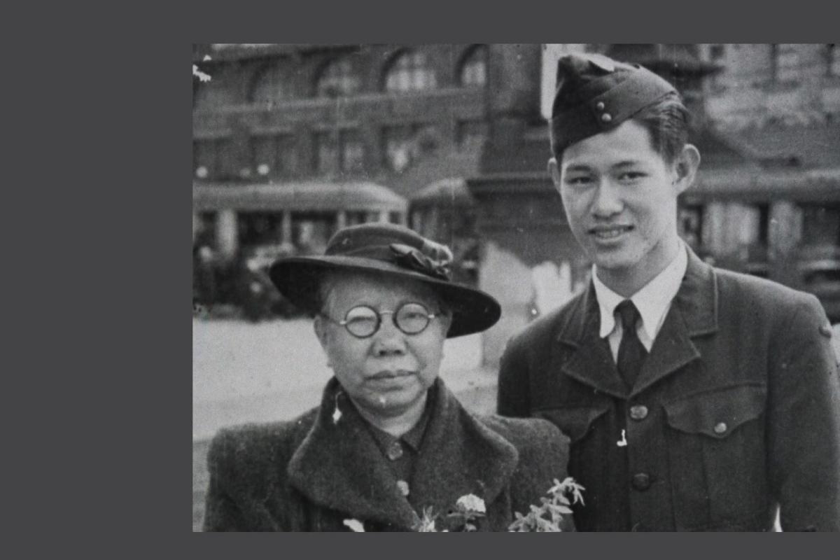Black and white photo. Young man in RAAF uniform stands next to elderly woman holding a bouquet of flowers.