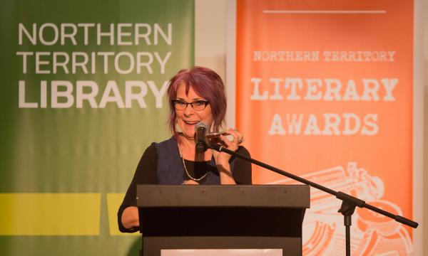 Woman standing at lectern with microphone smiling