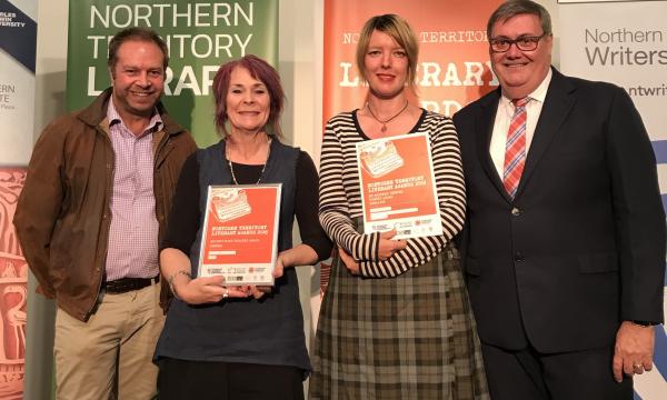 A man, two women and a man posing for the camera. Two women holding orange certificates
