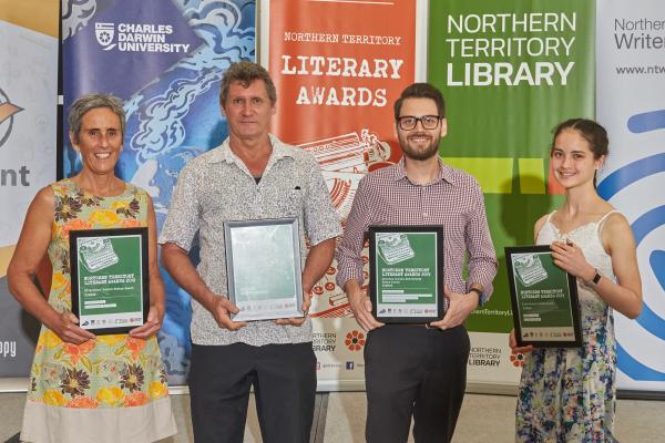 Four people standing and posing with winners certificates in hand