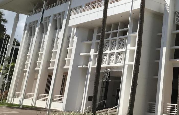 Large white building with geometric shapes and palm trees in the foreground