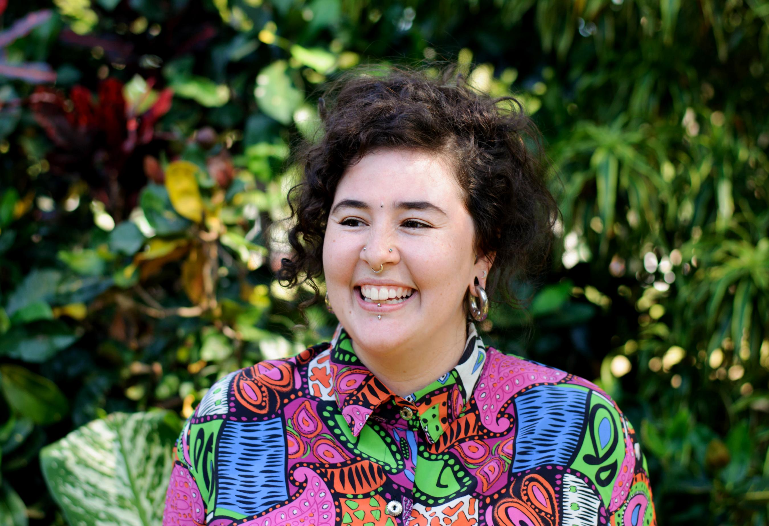 Smiling woman looking left of the image wearing a colourful shirt
