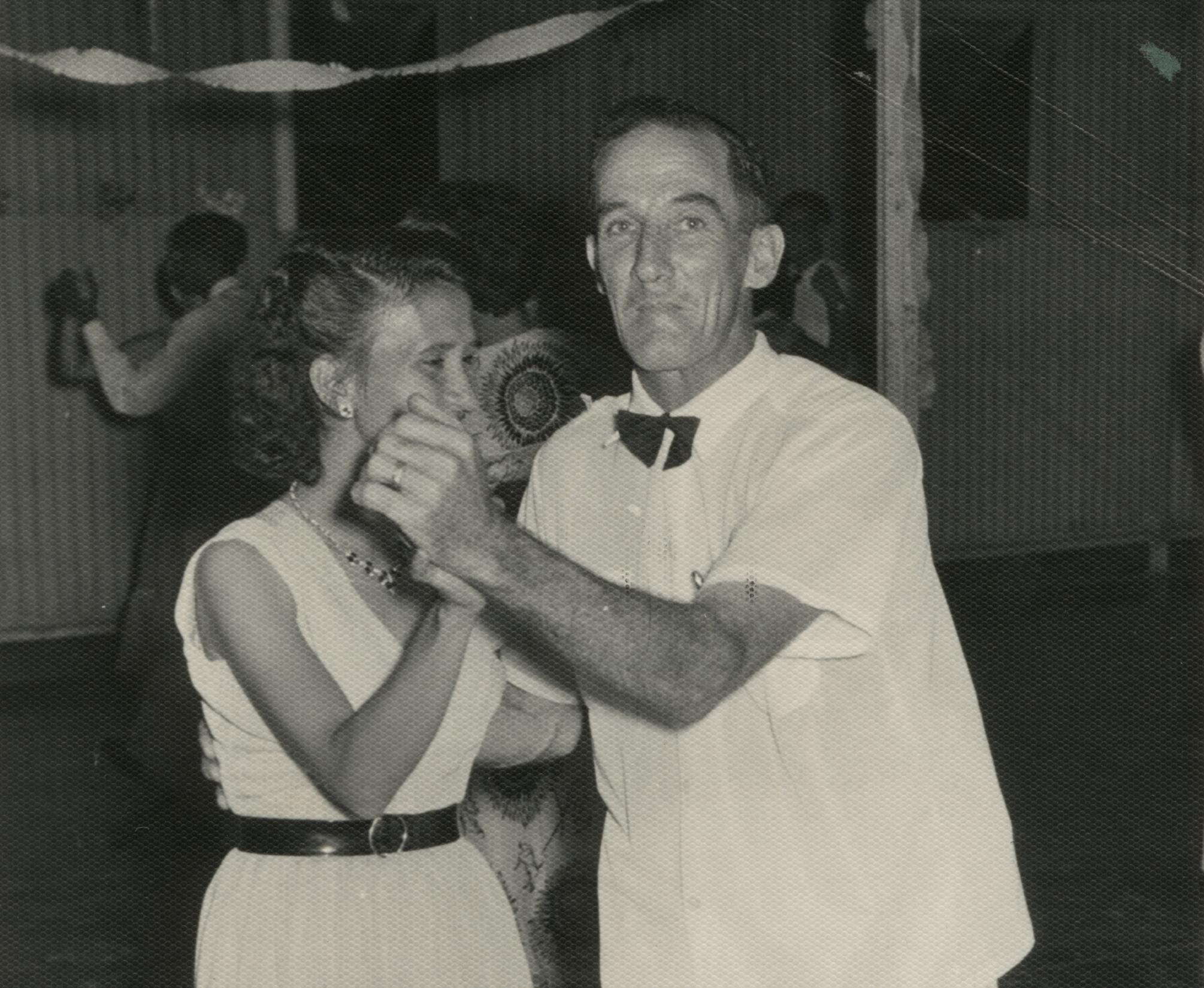 A woman and man dressed in white clothing dancing together