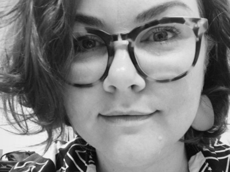 Black and White image of a woman (Alicia Scobie) wearing glasses looking at camera
