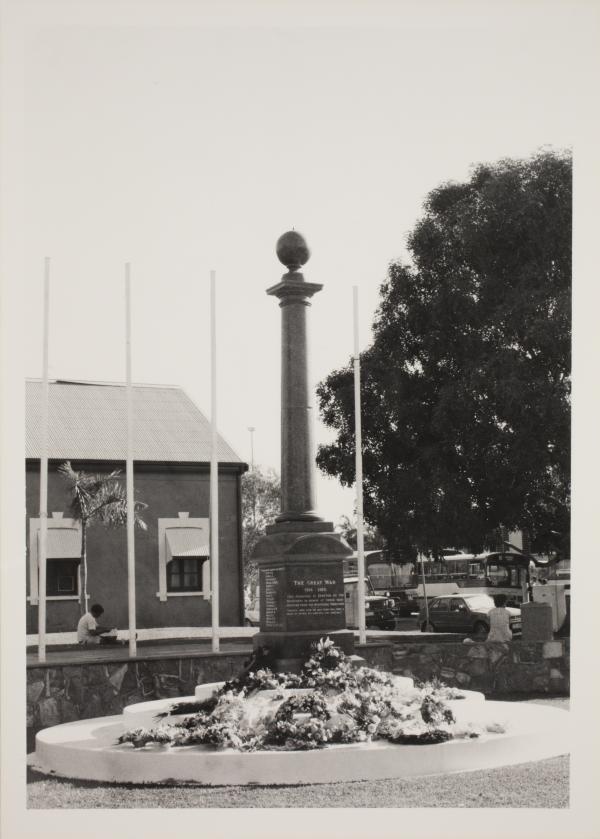 Cenotaph, 1985. Janet Chaloupka (photographer) Library & Archives NT, Janet Chaloupka Collection, PH0219/0265 The Cenotaph is at centre with floral wreaths at its base. In the background at left is a building (Browns Mart) and at right is a large tree. A bus can be seen in the far distance.