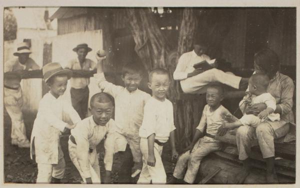 Several children play around a tree.